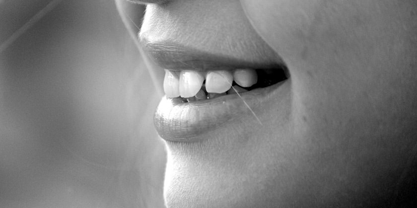 Foto de la boca de una mujer enseñando los dientes.